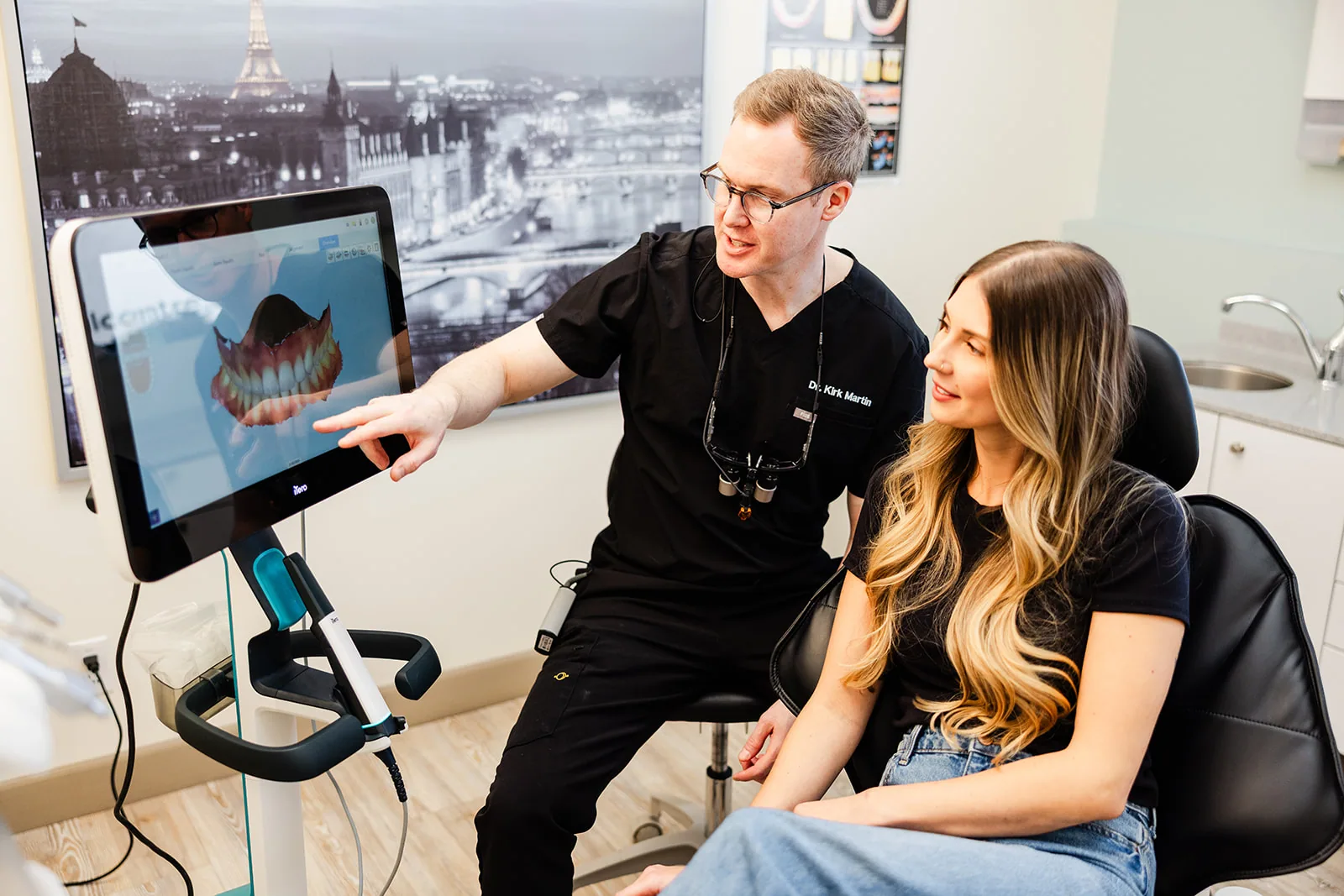 A dentist showing a patient their x-ray on a chairside screen